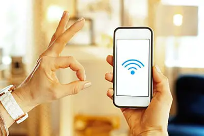 A hand holding a phone with a strong wifi icon