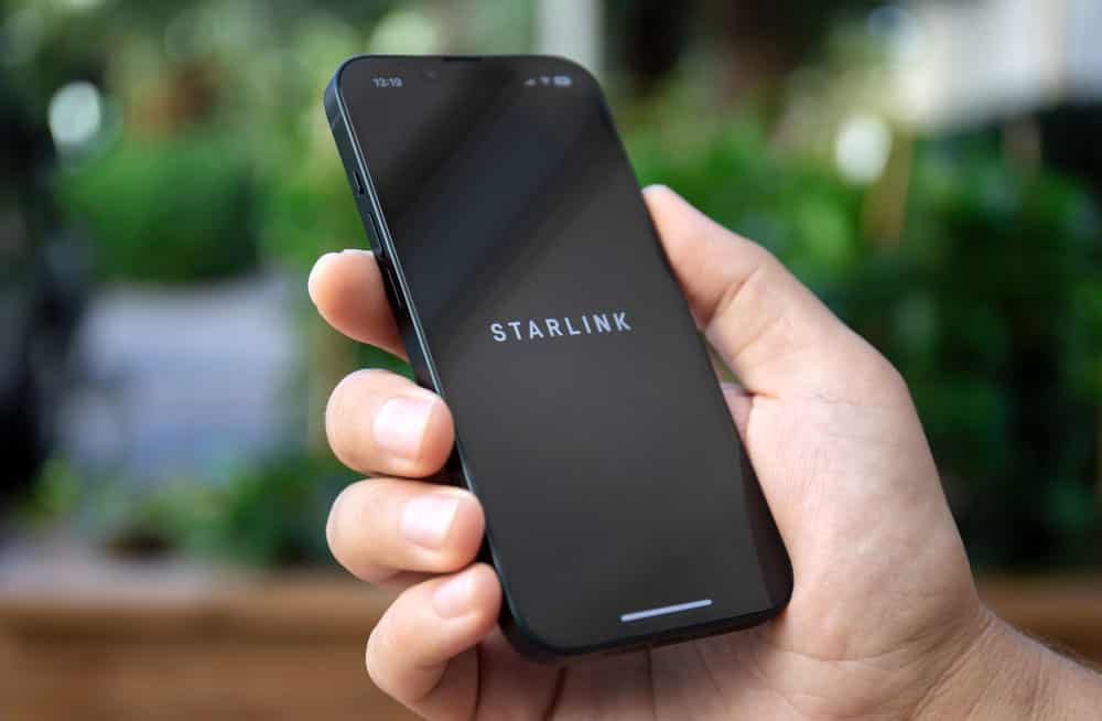 A man holding his iPhone 14 device with starlink