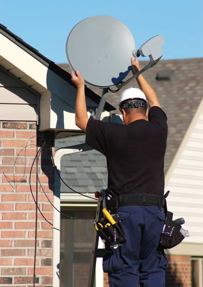 A Worker is mounting a Starlink Dish. 