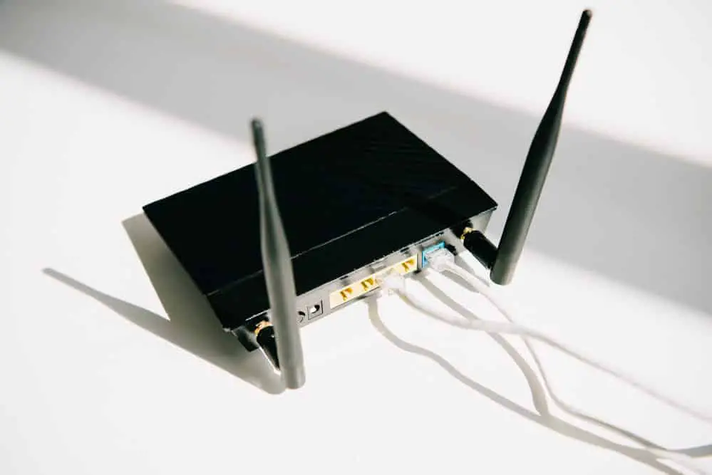Black plugged router on white office table in the sunshine  