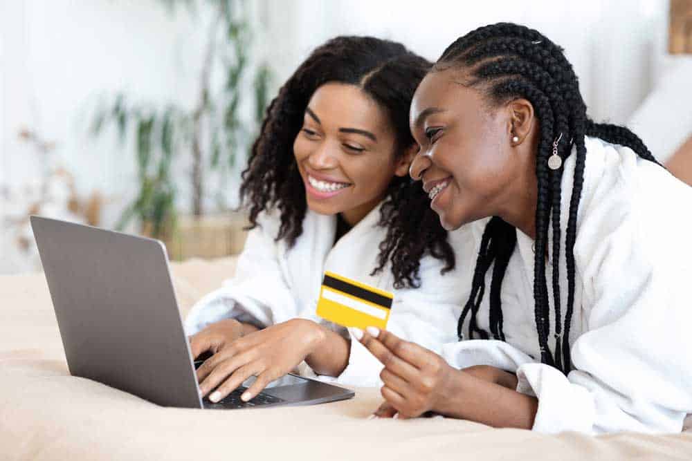 Two ladies are using a laptop to shop online.