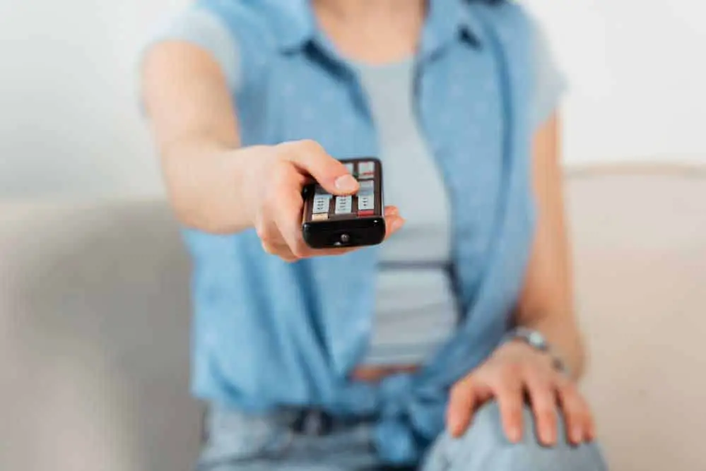 A Young Woman Clicking a Remote Controller. 
