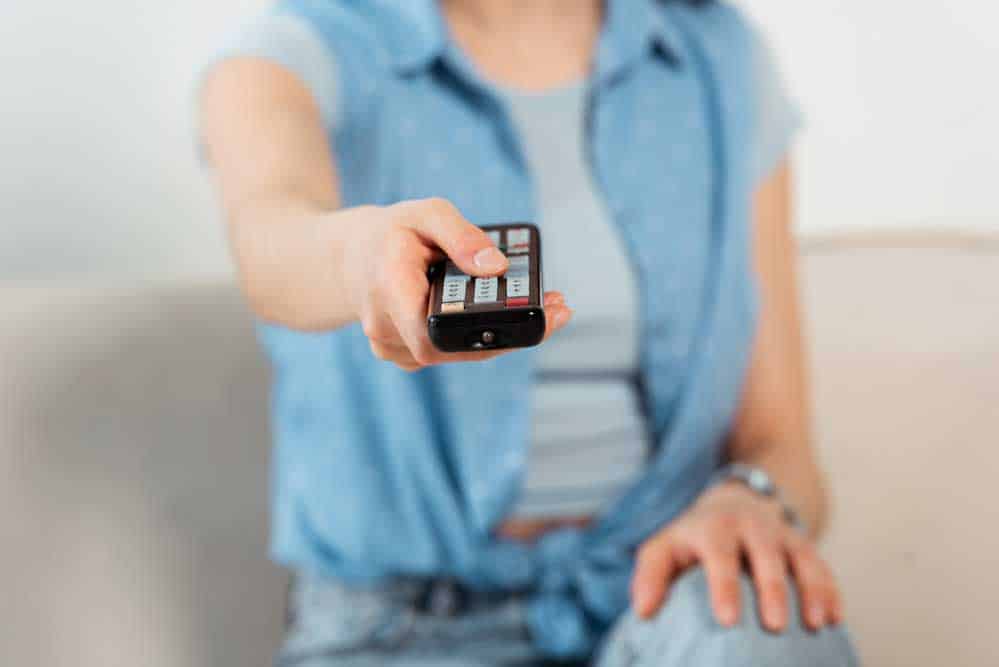 A Young Woman Clicking a Remote Controller.