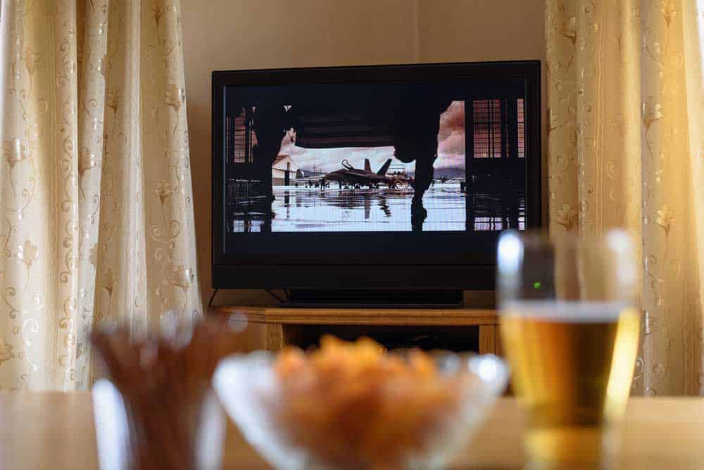 TV watching (movie) with snacks lying on the table.